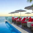 pool with red chairs and white umbrellas