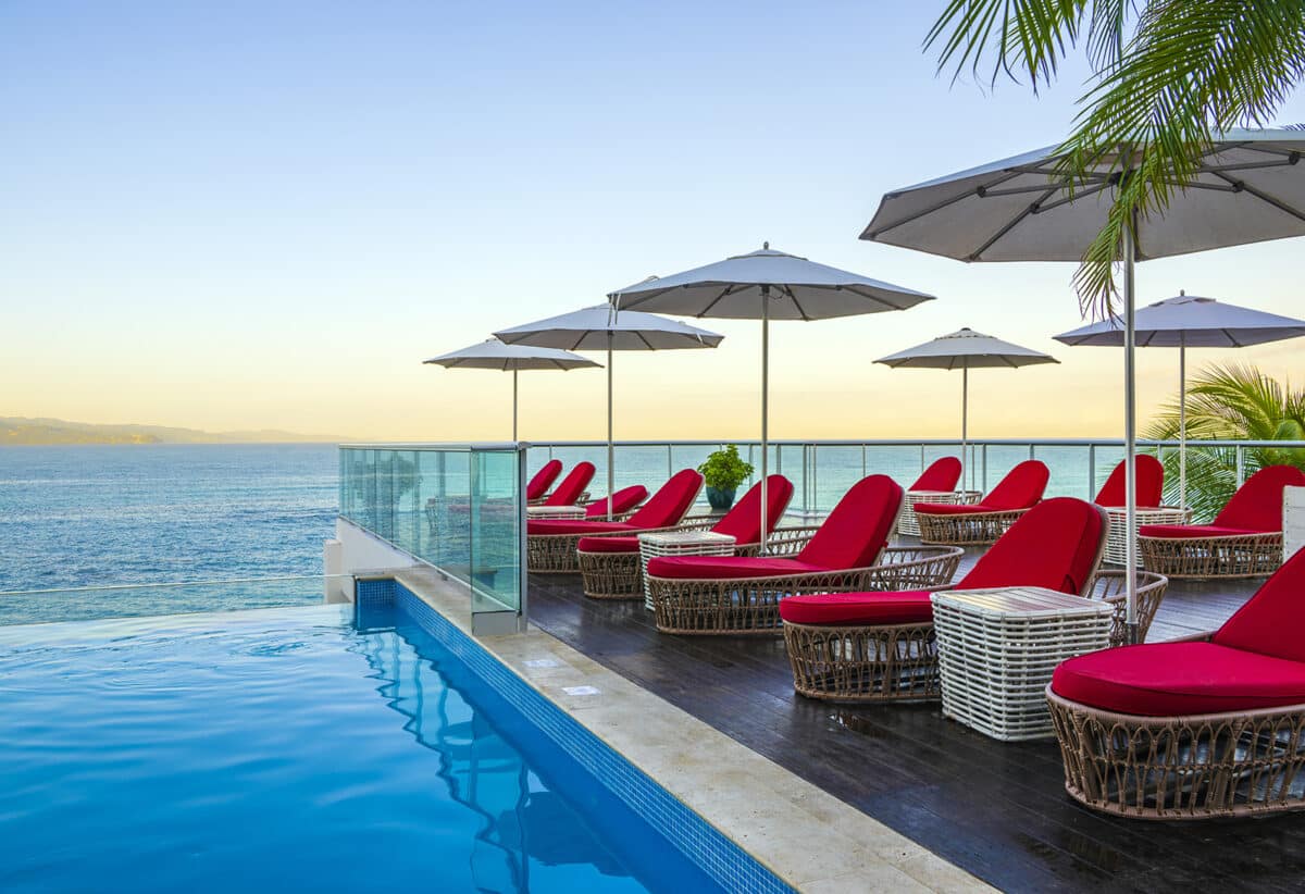 pool with red chairs and white umbrellas