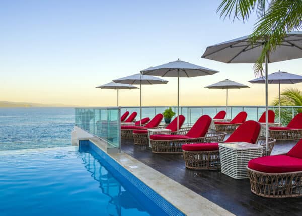 pool with red chairs and white umbrellas